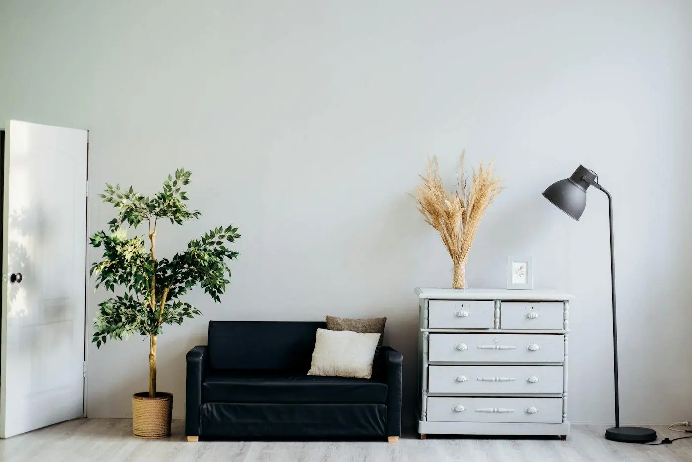 Zwarte vloerlamp naast een witte ladekast