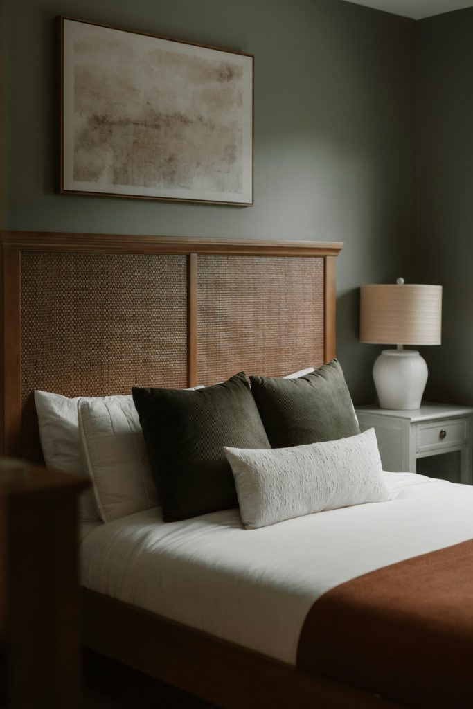 Bed met gestoffeerd rieten hoofdbord en groene en grijze kussens
