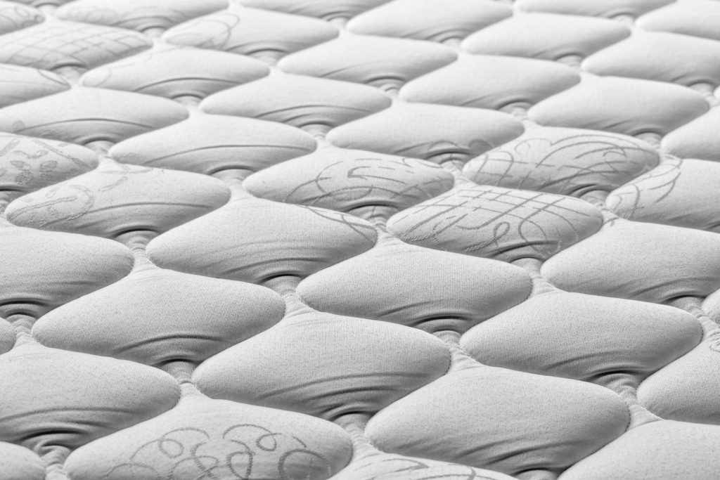 Close-up van de gewatteerde bovenkant van een witte matras
