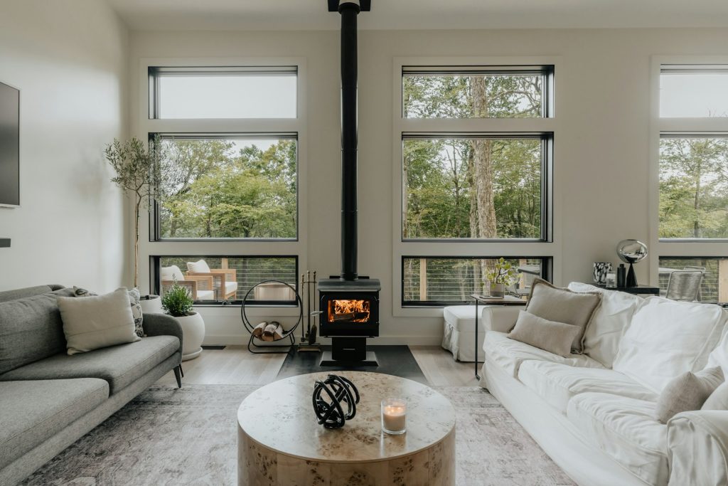 Lichte Scandinavische woonkamer met witte banken, houtkachel en grote ramen