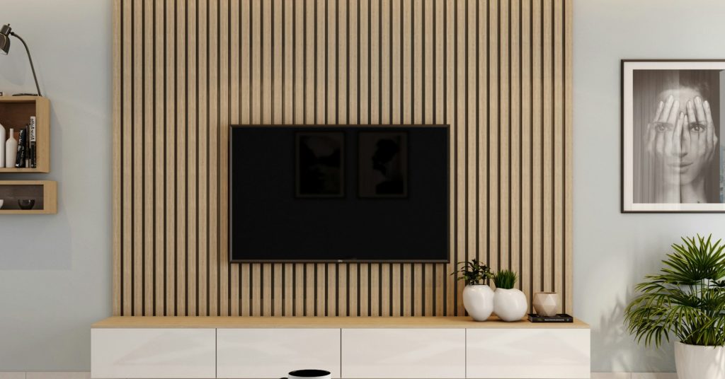 Tv aan een wand van lichte houten lamellen boven een wit tv-meubel