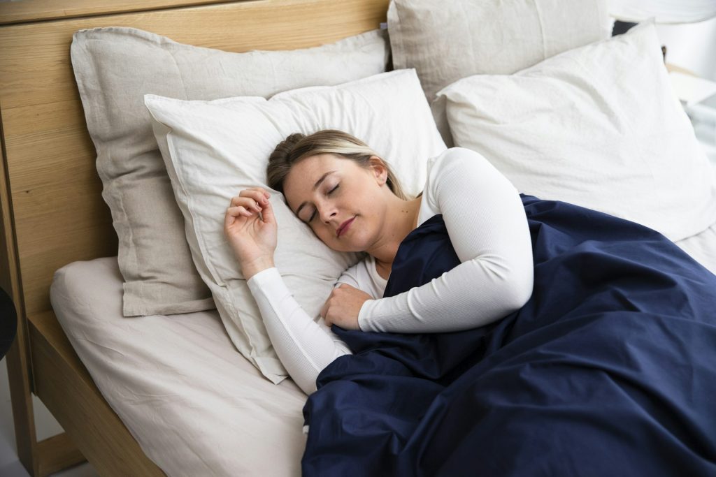 Vrouw slaapt op haar zij met een donkerblauw dekbed