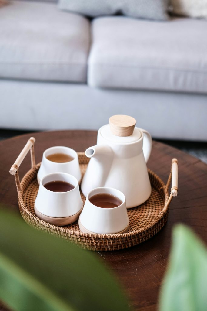 Witte keramiek theepot en kopjes op een rotan dienblad
